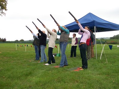 Girls aiming guns at clays in a crossing bird format